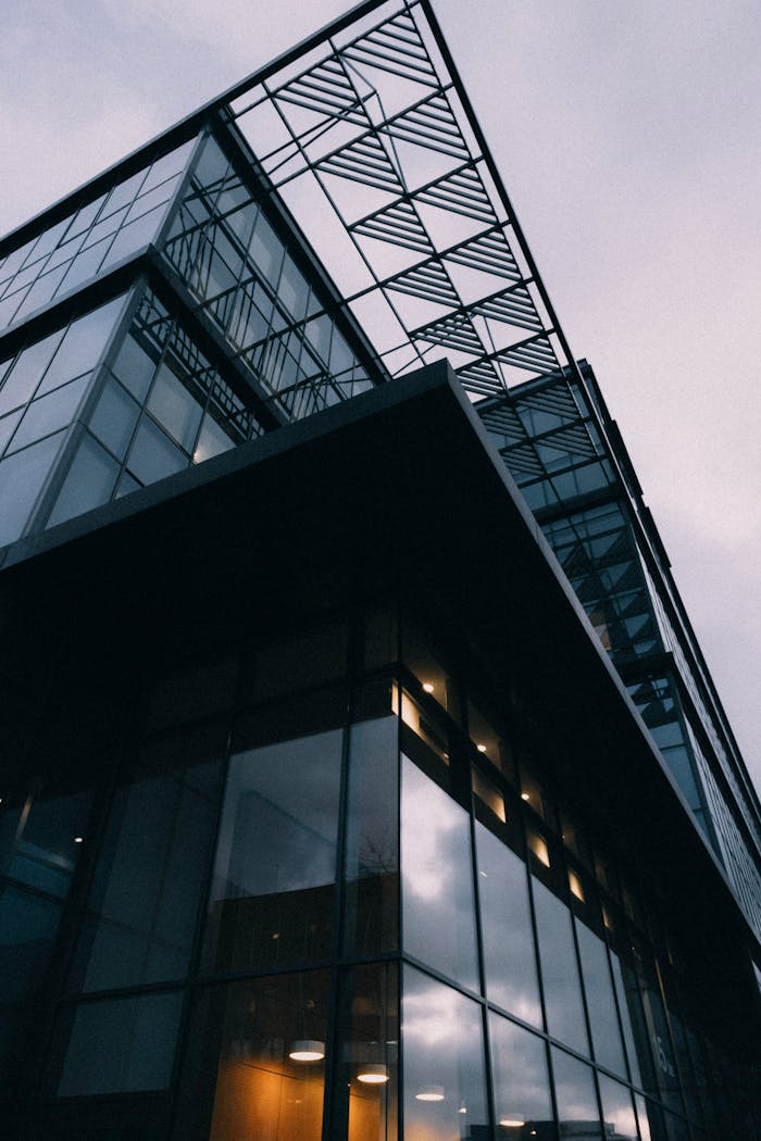Low-angle shot of a modern glass and steel building against a cloudy sky, capturing contemporary design.