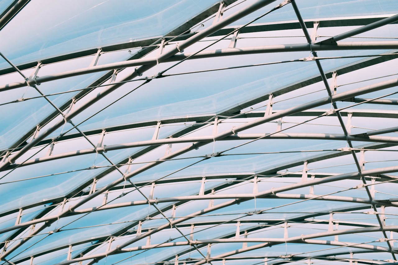 A low-angle shot of modern steel framework with geometric patterns against a clear blue sky.