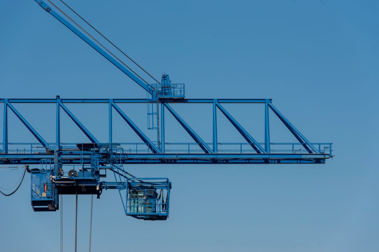 A blue industrial crane set against a clear sky, showcasing modern construction technology.