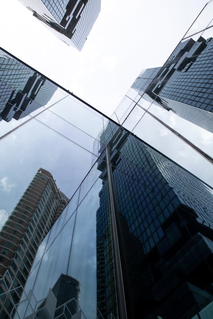 Modern glass skyscrapers reflect each other under a bright sky in Bangkok, Thailand.